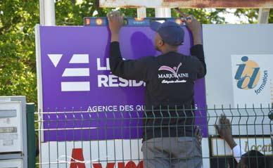 Un agent de Marjolaine Entreprise en pleine pose d'une signalétique extérieure 